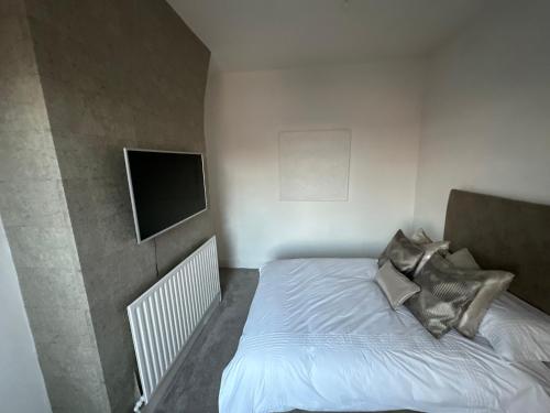 een kleine slaapkamer met een bed en een flatscreen-tv bij 3 Bedroom House on Beatles Famous Road in Liverpool