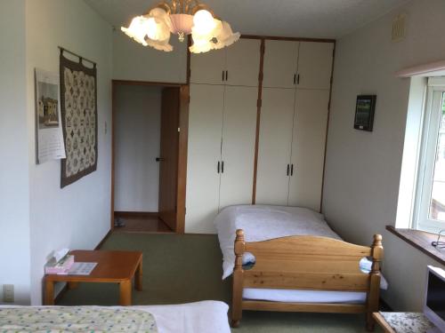 a bedroom with a bed and a table and a chandelier at Natsumi no Sato in Biei