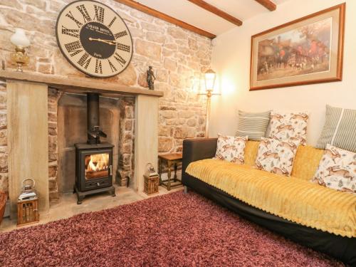 a living room with a couch and a clock on the wall at The LA'AL Cragg in Kirkby Stephen