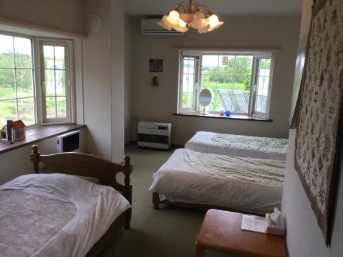 a bedroom with two beds and two windows at Natsumi no Sato in Biei