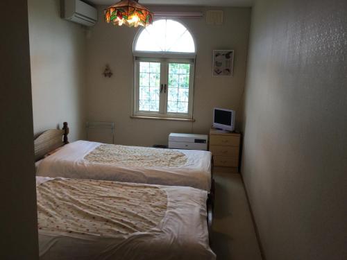 two beds in a room with a window at Natsumi no Sato in Biei