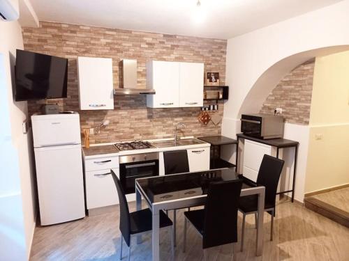 una cocina con electrodomésticos blancos, mesa y sillas en 'Al Vico Dante' en Loceri