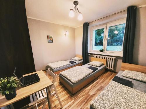 a room with three beds and a table with a laptop at Tanie spanie na Grunwaldzkiej - ZAMELDOWANIE BEZOBSŁUGOWE- in Bydgoszcz