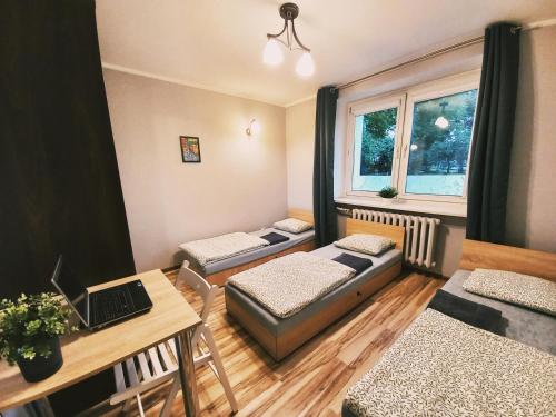 Habitación con 3 camas y mesa con ordenador portátil. en Tanie spanie na Grunwaldzkiej - ZAMELDOWANIE BEZOBSŁUGOWE- en Bydgoszcz