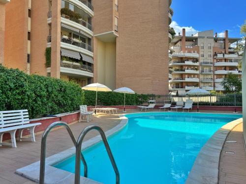 a swimming pool with chairs and umbrellas next to a building at Rome Suite Talenti in Rome
