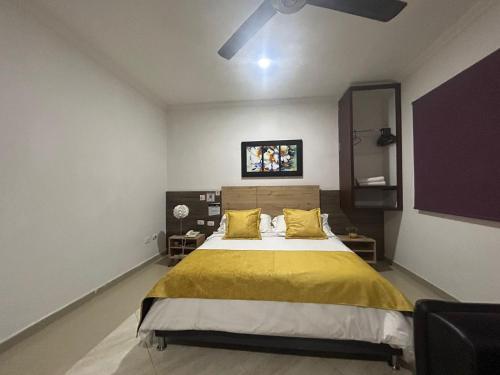 a bedroom with a large bed with a yellow blanket at Hotel La Casa 1 in Montería