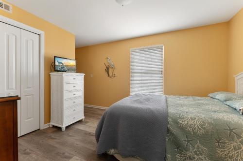 um quarto com paredes amarelas, uma cama e uma cómoda em Nw Condo W Ocean View, Sundeck, Pool em North Wildwood