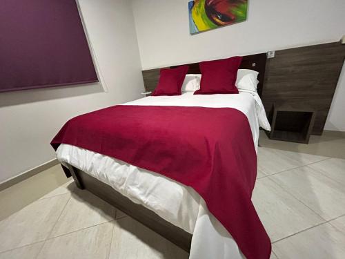 a bedroom with a large bed with red pillows at Hotel La Casa 1 in Montería