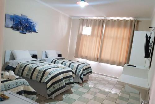a room with two beds and a television in it at Suite Independente Arouche Duplo ou Triplo in Sao Paulo