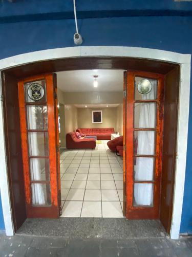 an open door into a living room with a red couch at Lurviz Home Suítes in Cabo Frio