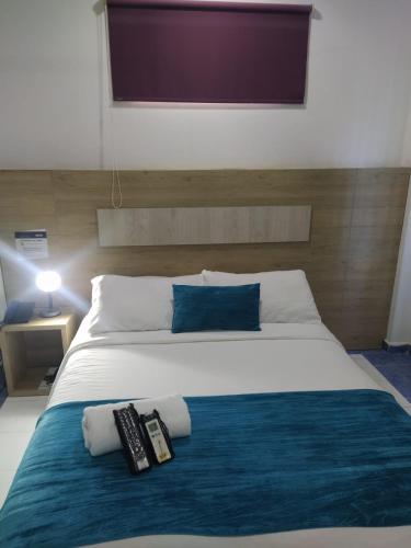 a bedroom with a large bed with two remote controls on it at Hotel La Casa 1 in Montería