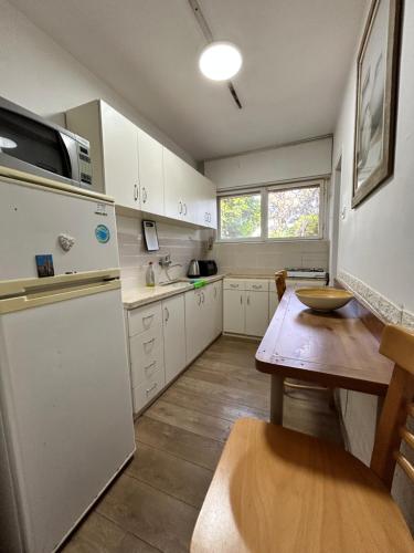 a kitchen with white cabinets and a wooden table at 3-х комнатная квартира у моря в Хайфе in Haifa