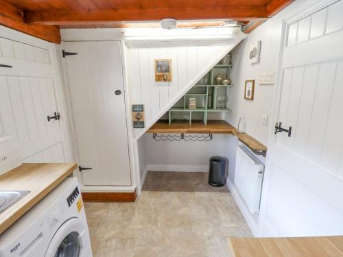 a small kitchen with white cabinets and a staircase at The Cottage 16 Northside in Patrington
