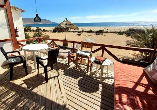 um deque de madeira com uma mesa e cadeiras na praia em Cabañas Paraiso em Bahia Inglesa