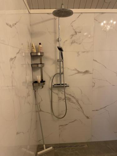 a shower in a bathroom with white marble walls at Skärhamns Paradis in Skärhamn