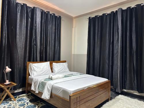 Schlafzimmer mit einem Bett und schwarzen Vorhängen in der Unterkunft Pai4 Apartments 2 in Dodoma