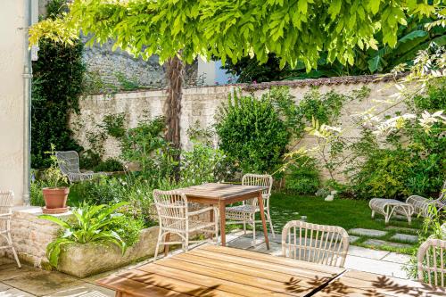 ラ・ロシェルにあるChambres d'Hôtes Eden Ouestの木製のテーブルと椅子が置かれた庭園