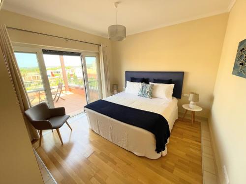 a bedroom with a bed and a chair and a balcony at Penthouse Victoria in Vilamoura
