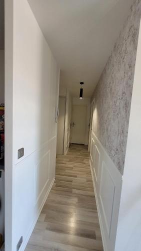 un couloir vide avec des murs blancs et du parquet dans l'établissement Cosy Home Paris, à Carrières-sous-Poissy