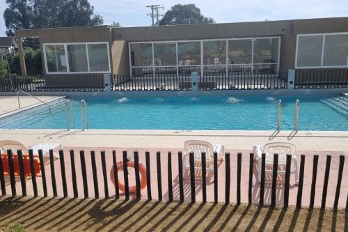 a swimming pool with a fence and chairs in it at Depto. Nuevo Algarrobo patio privado in Algarrobo