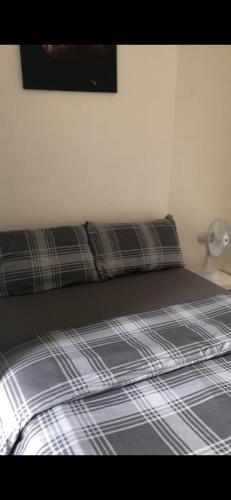 Una cama en un dormitorio con una sábana de cuadros y una lámpara. en W13 x Weekly Monthly Discount, en Londres