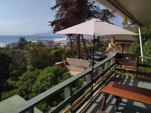 a balcony with a table and an umbrella at Cabañas El Bosque in Maitencillo