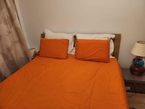 1 cama con edredón de naranja y 2 almohadas en Logement YJR, en Pierrefitte-sur-Seine