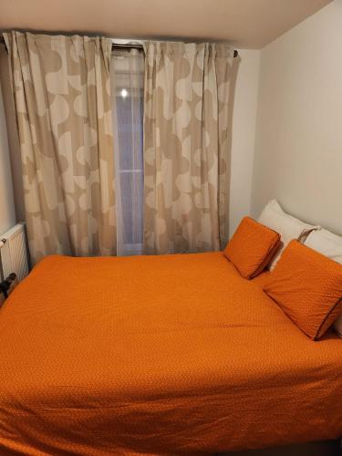 1 dormitorio con 1 cama de color naranja y 2 almohadas de color naranja. en Logement YJR, en Pierrefitte-sur-Seine