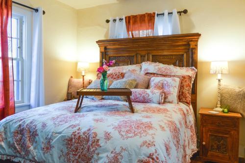 a bed with a wooden headboard and a vase with flowers on it at Cozy Adobe Casita 1 Mile to Santa Fe Plaza! in Santa Fe