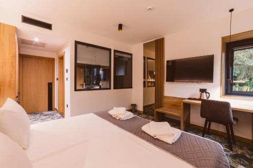 a bedroom with a bed and a desk and a television at Hotel Boutique Anoma in Sarajevo