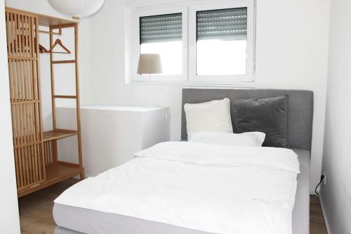 1 dormitorio con 1 cama blanca y 2 ventanas en Schöne EG-Neubauwohnung in Bad Soden, en Bad Soden am Taunus