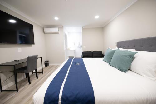 a bedroom with a large bed and a desk at Omeo Suites in Alhambra