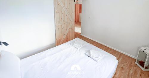 a bedroom with a white bed with two white bow ties on it at Tramonto Apartments Zator Przeciszów in Zator