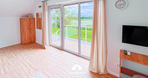 a living room with a tv and a balcony at Tramonto Apartments Zator Przeciszów in Zator