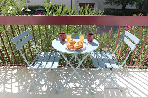 une table avec une assiette de pain et deux verres de jus d'orange dans l'établissement Appartement Briggia - Welkeys, à Montpellier