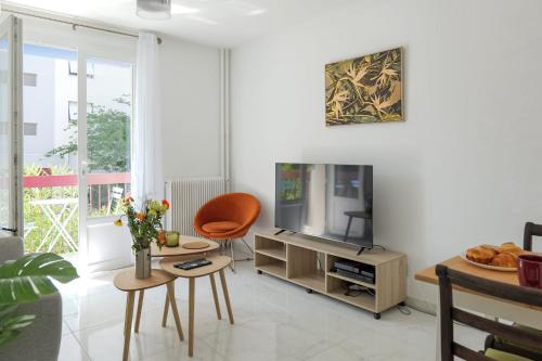 un salon avec une télévision, une table et des chaises dans l'établissement Appartement Briggia - Welkeys, à Montpellier