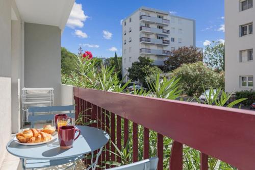 une table avec une assiette de nourriture sur un balcon dans l'établissement Appartement Briggia - Welkeys, à Montpellier