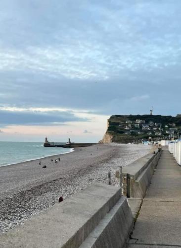 a beach with people on the sand and the ocean at Le Gîte Du Jardin in Colleville