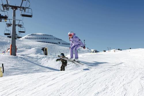 a woman and a child on skis in the snow at RUHESTUBE - Cozy Apartment with Balcony & Parking in Zillertal, presented by AlpenLuxus in Fügen