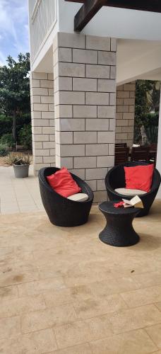two black chairs with red pillows on a patio at Superb large private villa with pool in Prainha