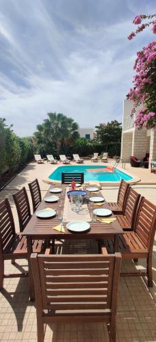 a wooden table with chairs next to a pool at Superb large private villa with pool in Prainha