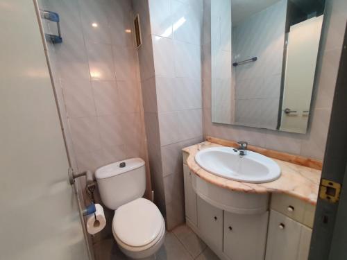 La salle de bains est pourvue de toilettes, d'un lavabo et d'un miroir. dans l'établissement apartamento con vistas al mar a pocos metros de la playa, à Valence