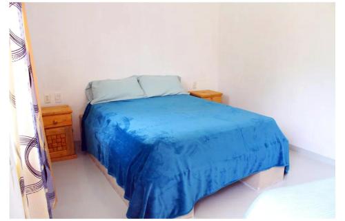 uma cama num quarto com um cobertor azul em Chentes Place em Barra de la Cruz