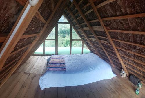 a bed in a attic with a large window at Gocta Dulce Hogar in Cocachimba