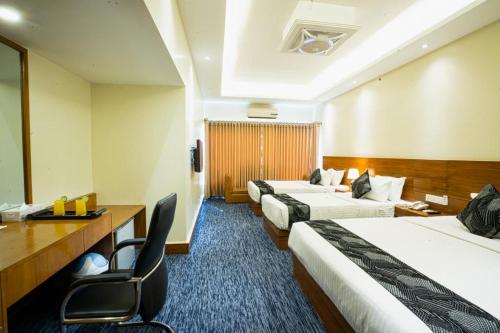 Habitación de hotel con 2 camas y escritorio en Richmond Hotel & Suites, en Dhaka