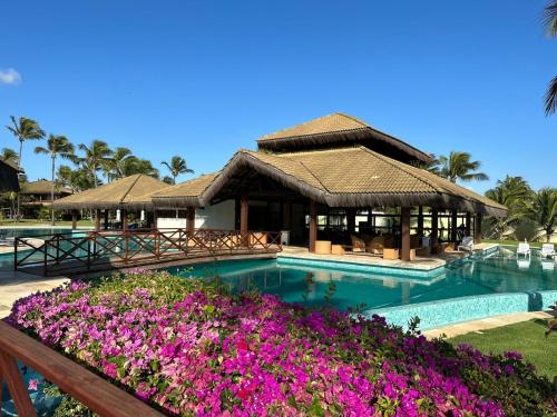 un resort con piscina con fiori viola di Bangalô Eco Residence Flecheiras a Flecheiras