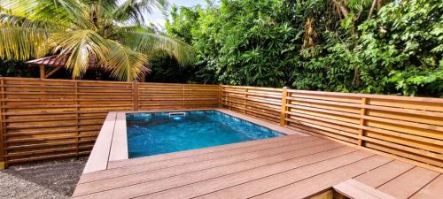 a swimming pool with a wooden fence and a wooden deck at Soley'Caraibes III in Les Trois-Îlets