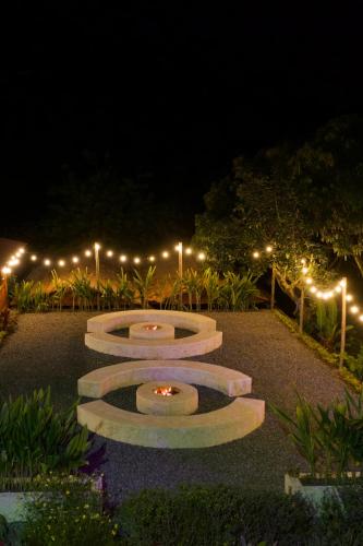 a park at night with three stone benches with lights at Hotel Campestre la Playa in Betania