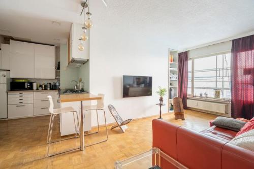 ein Wohnzimmer mit einem roten Sofa und einer Küche in der Unterkunft A 3 km du centre ville in Brüssel