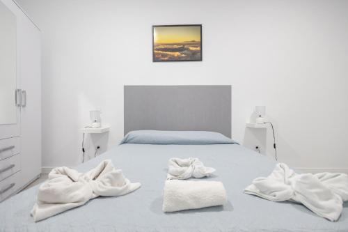 a white bedroom with a bed with towels on it at Lightbooking 7 Palmas in Las Palmas de Gran Canaria